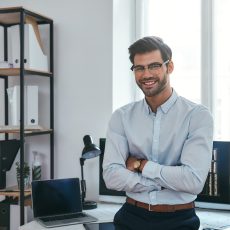 Happy trader. Cheerful businessman in formal clothes and eyeglasses is keeping arms crossed, smiling Happy trader. Cheerful businessman in formal clothes and eyeglasses is keeping arms crossed, smiling